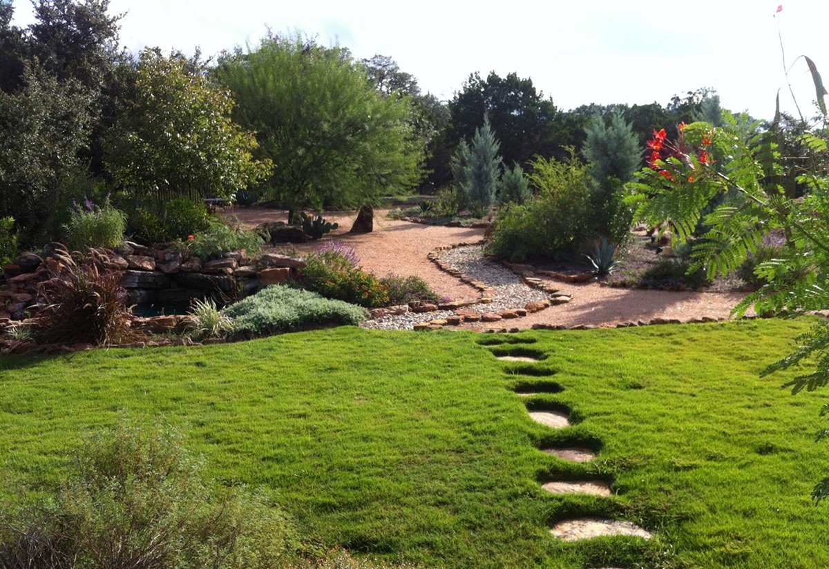 A garden with a stone path leading to a pond.